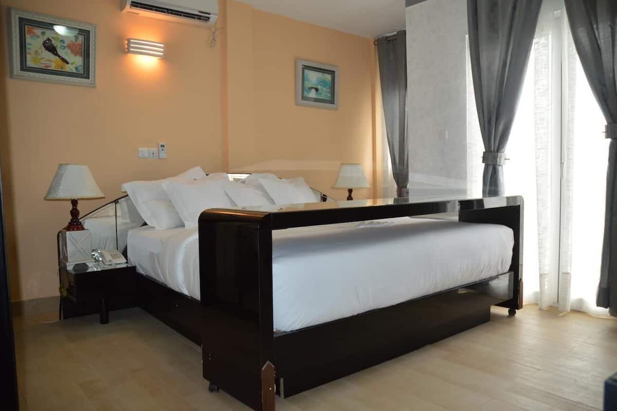 Una camera da letto con un letto, due comodini, una lampada e un condizionatore d'aria a parete.