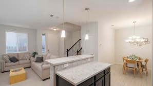 A modern living room with a sofa, a coffee table, and a dining area with a table and chairs. - Local 3BD/2.5BA - WiFi & Parking (Carson City)