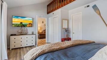 Un dormitorio con cama, cómoda, televisor y escalera de madera.