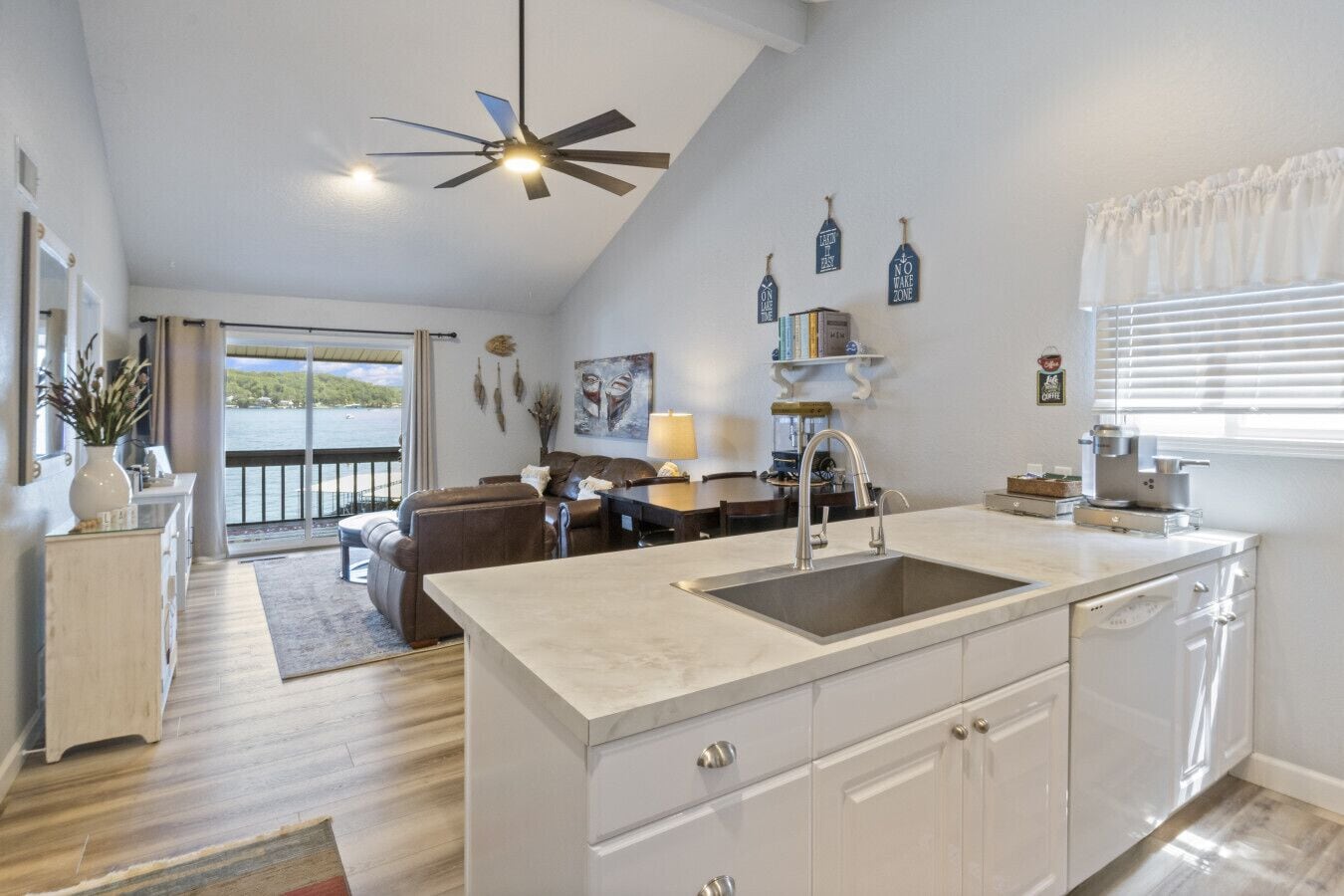 Una cocina moderna con una isla grande, armarios blancos y vistas al exterior.
