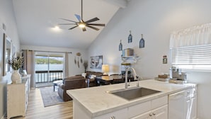 A modern kitchen with a large island, white cabinetry, and a view of the outdoors.
