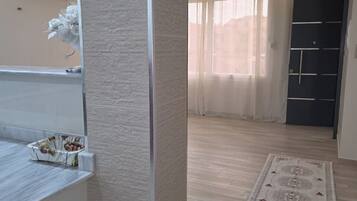 Ein zeitgemäßes Interieur mit hellem Bodenbelag, einem gemusterten Teppich und einer Tür mit schwarzem Einsatz.