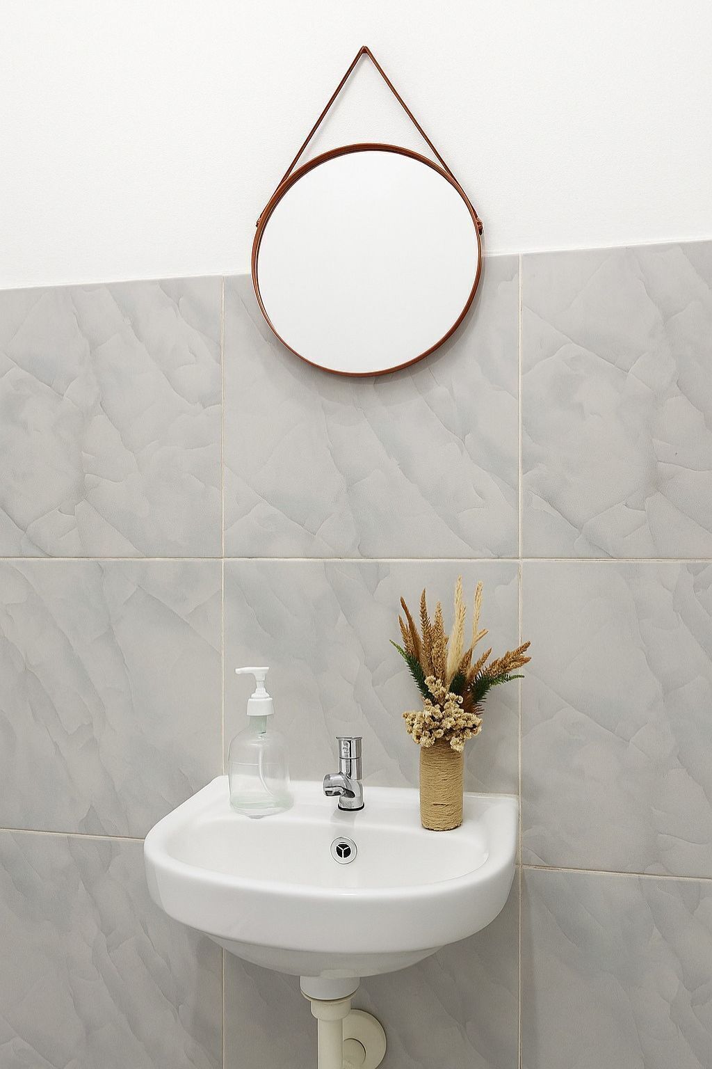 A bathroom with a white sink, a mirror, and a decorative vase.