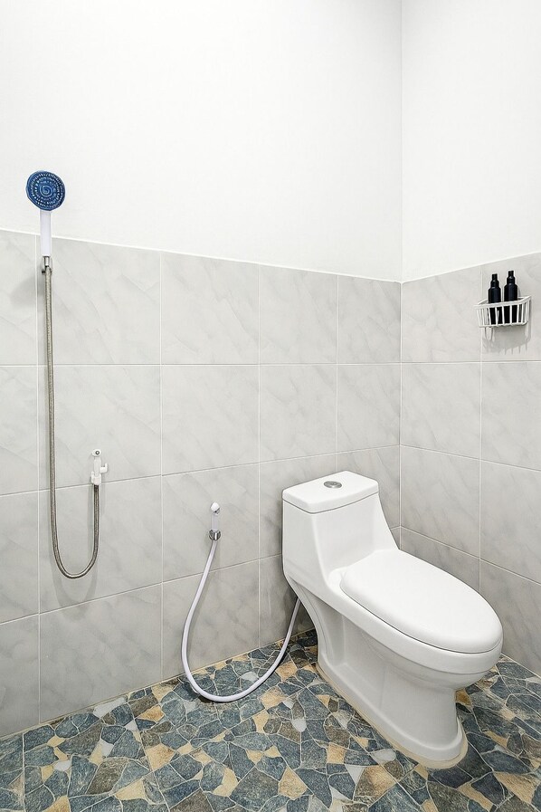 A bathroom with a toilet, a shower, and a tiled floor.