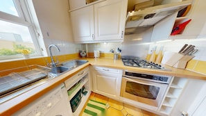A compact kitchen with a sink, stove, oven, and white cabinets. - Castle Mill View, sleeps 4. (Central Oxford)