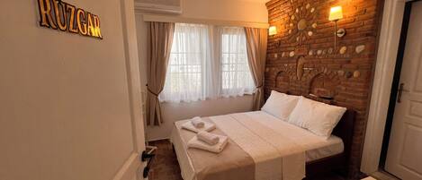 Habitación de hotel con una cama, un muro de ladrillo y un cartel que dice "RÜZGAR".