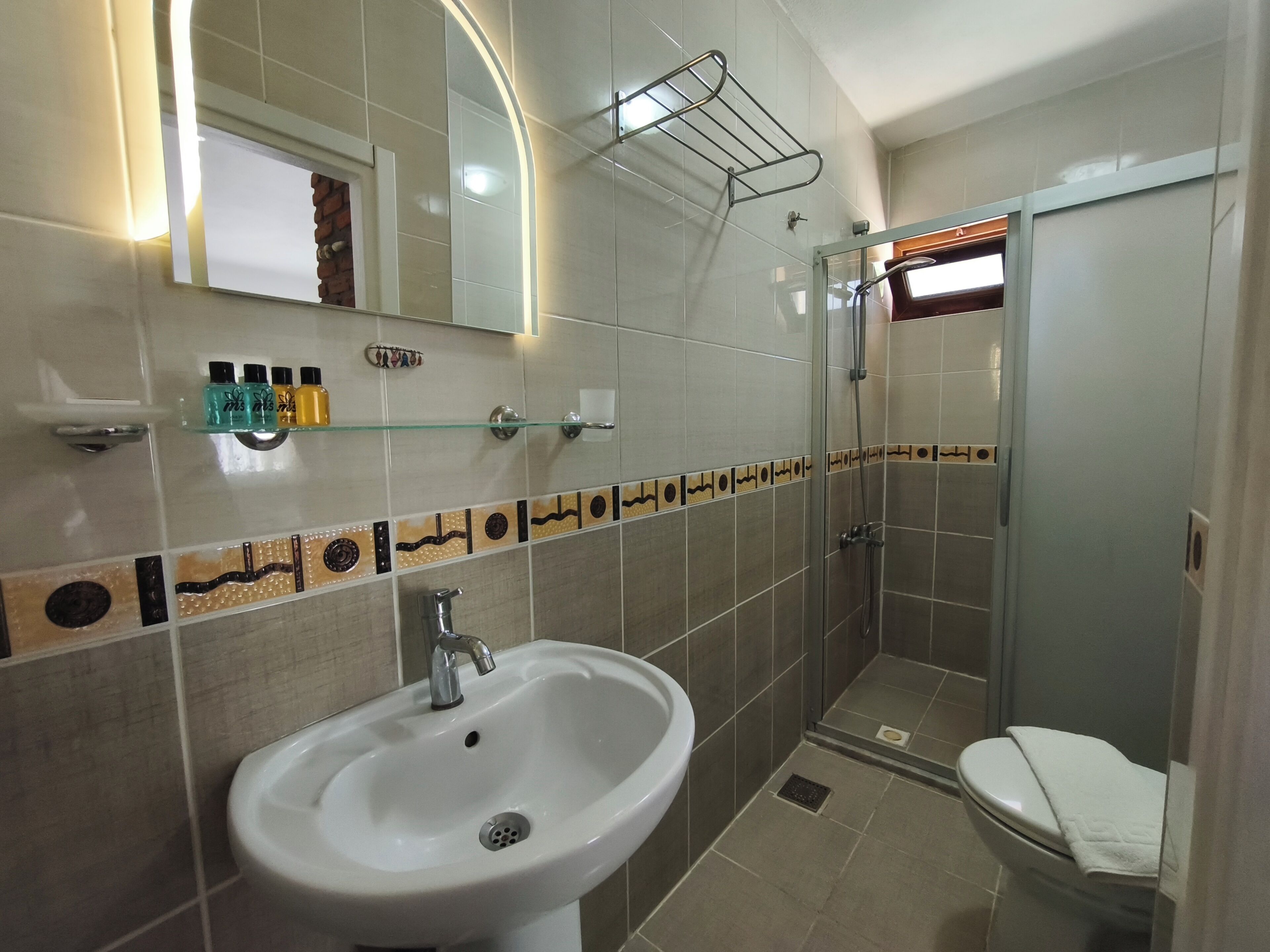 Ein Badezimmer mit Waschbecken, Spiegel, Dusche und Toilette.
