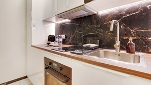 A modern kitchen with a marble backsplash, stainless steel sink, and wooden countertop. - Elegant 4P Studio in the Heart of Montmartre - Paris (Paris)