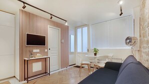 A modern living room with a sofa, TV, and a small table with chairs. - Elegant 4P Studio in the Heart of Montmartre - Paris (Paris)