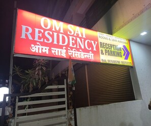 Un cartel de hotel con la indicación "OM Sai Residency" y las direcciones a "Recepción y estacionamiento".