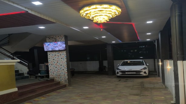 Un vestíbulo con piso de baldosas, una escalera, una araña y un coche estacionado en su interior.