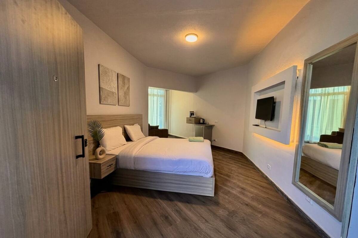 Una camera da letto con un letto, comodini, una TV e uno specchio.