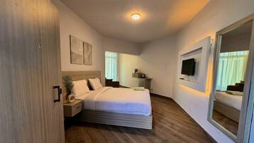 Un dormitorio con cama, mesitas de noche, televisión y espejo.