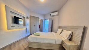 Una camera da letto moderna con un letto grande, una TV a parete e un condizionatore d'aria.