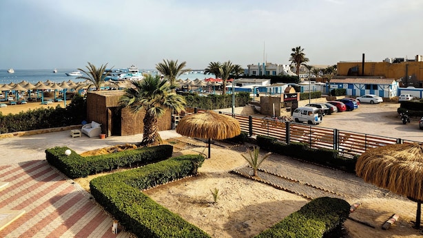 Un hotel sulla spiaggia con un'area parcheggio, ombrelloni e vista mare.