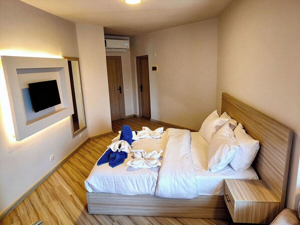 Ein Hotelzimmer mit einem Bett, einem an der Wand montierten Fernseher und einer Klimaanlage.
