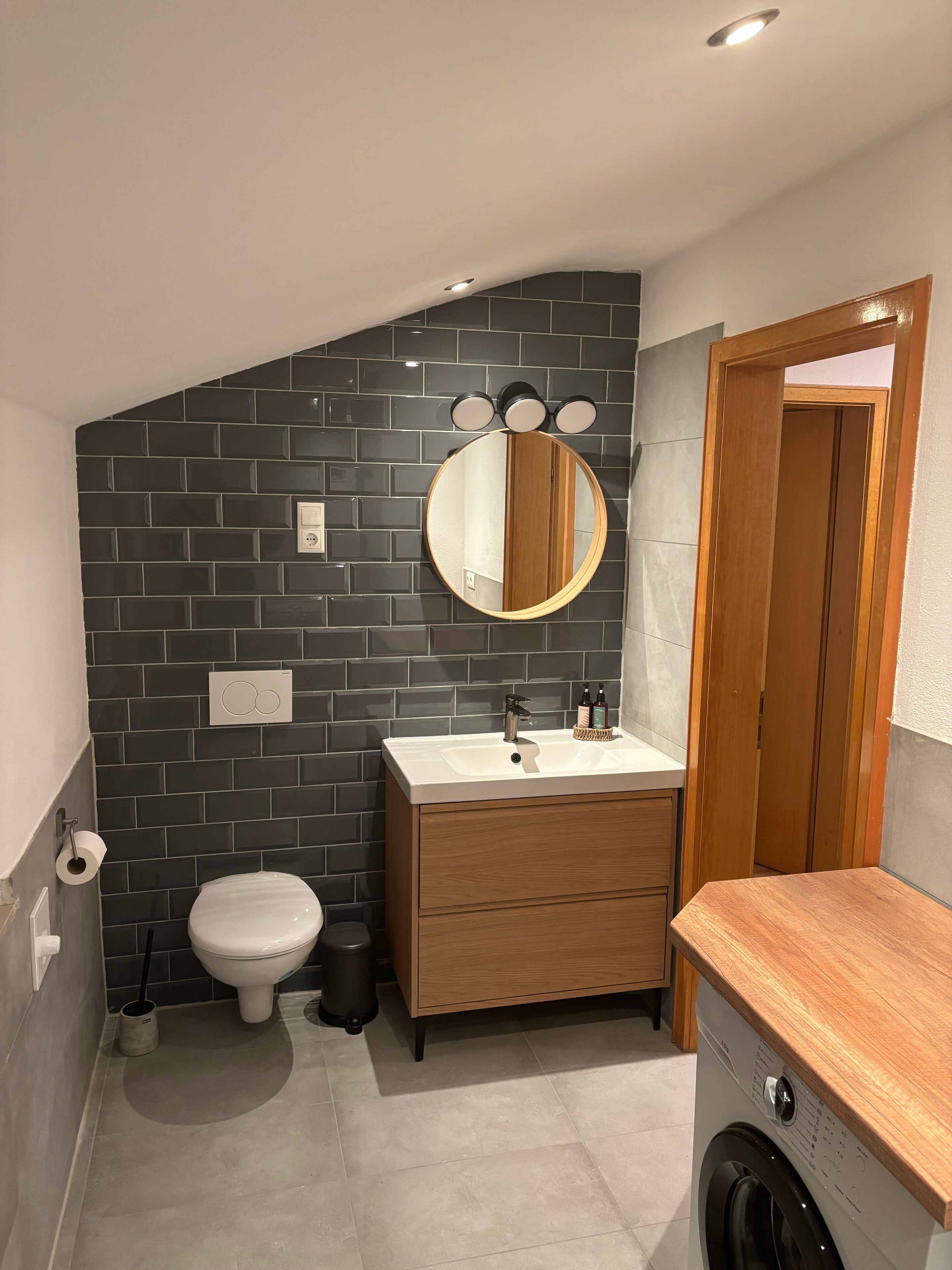 Une petite salle de bain comprenant des toilettes, un lavabo et un lave-linge.