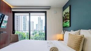 Una habitación de hotel con una cama grande, televisión, vista a la ciudad y un cuadro en la pared.