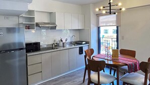 Una cocina moderna con refrigerador empotrado, electrodomésticos de acero inoxidable y un comedor con sillas y mesa de madera.