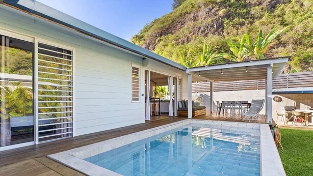 A modern house with a swimming pool, a patio with outdoor furniture, and a hillside view. - Private 3BR Villa with pool (Moorea-Maiao)