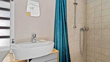 A bathroom with a white sink, a mirror, a shower, and a teal shower curtain.