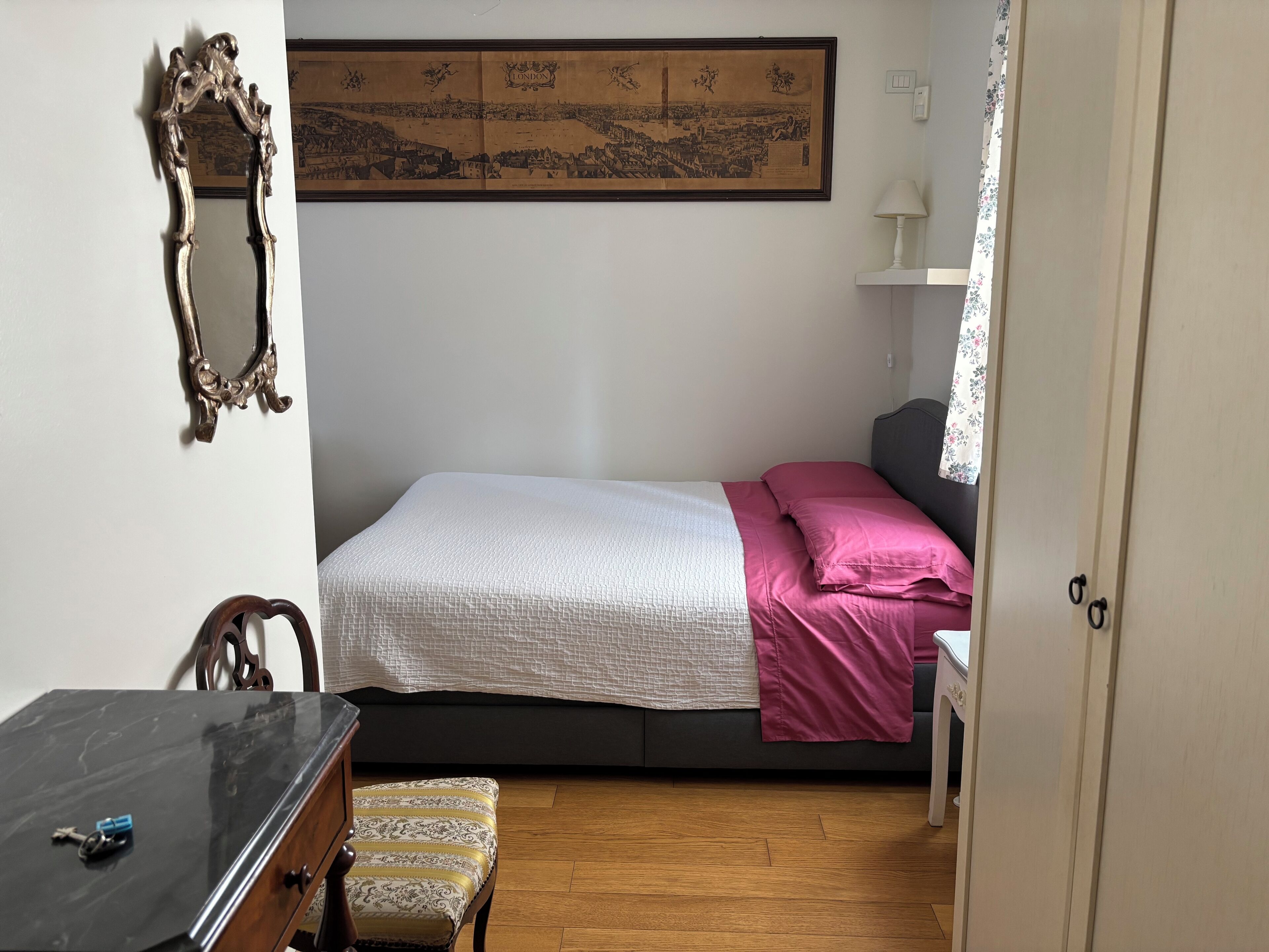 Une chambre à coucher avec un lit, un bureau, une chaise, un miroir et une carte encadrée accrochée au mur.