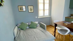 A bedroom with a bed, a desk, and a window.