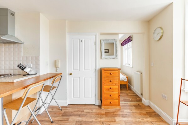 A compact kitchen with a wooden countertop, a white door, a wooden dresser, and a mirror on the wall.