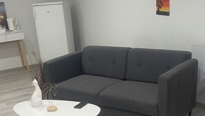 Un salon moderne avec un canapé gris, une table basse blanche et un petit vase décoratif.