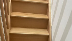 Un escalier en bois, avec une main courante sur le côté gauche, mène à un palier.