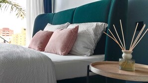 A hotel room with a bed, a bedside table with a reed diffuser, and a view of buildings outside. - Luxury Nest with Panoramic Wiews 10 min from Loro Park (Los Realejos)