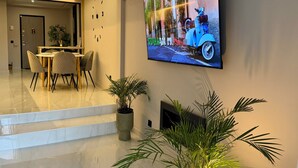 A modern living room with a flat-screen TV, a dining area with chairs, and a staircase leading to another level. - Luxury Nest with Panoramic Wiews 10 min from Loro Park (Los Realejos)
