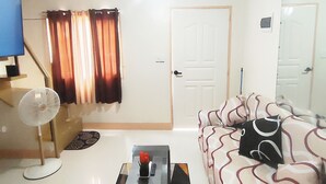 Una sala de estar con un sofá, una mesa de centro, un televisor y una puerta.