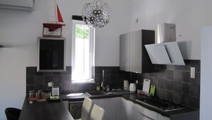 A modern kitchen with a dining table, chairs, a window, and a unique chandelier. - Cool 2-bedroom apartment with AC in Szeged (Szeged)