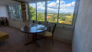 Un comedor con una mesa redonda, sillas y vistas a un paisaje montañoso a través de amplios ventanales.