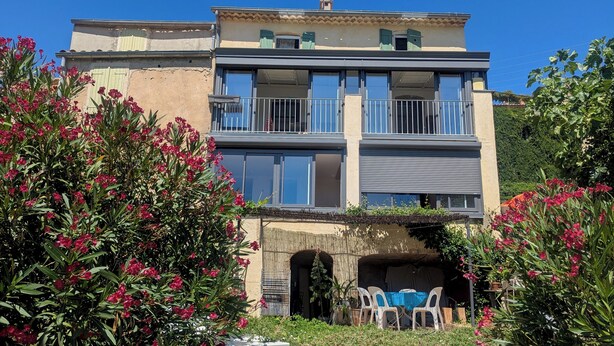 Un edificio de dos pisos con balcones, un vestíbulo cubierto y asientos al aire libre.