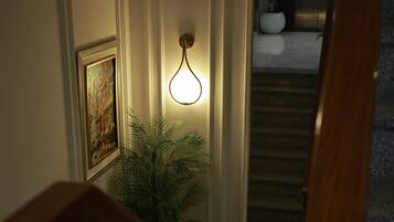 Uma escada com corrimão de madeira, luminária fixada na parede e um quadro emoldurado.