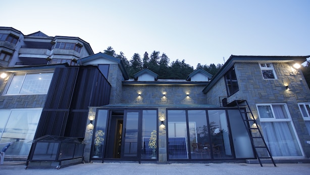 A modern building with large glass doors, a metal staircase, and stone walls.