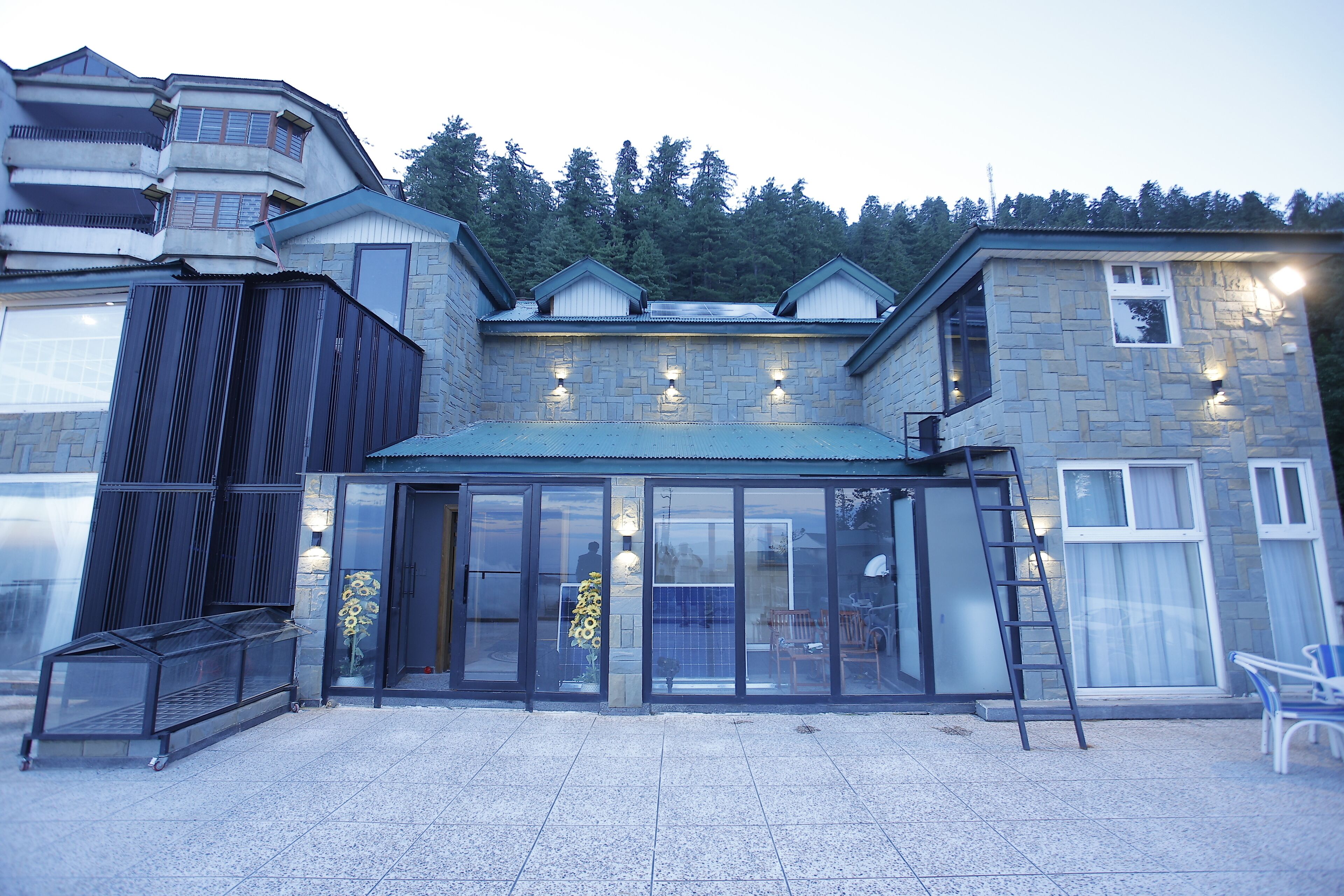 A modern building with a glass entrance, a stone facade, and a metal roof.