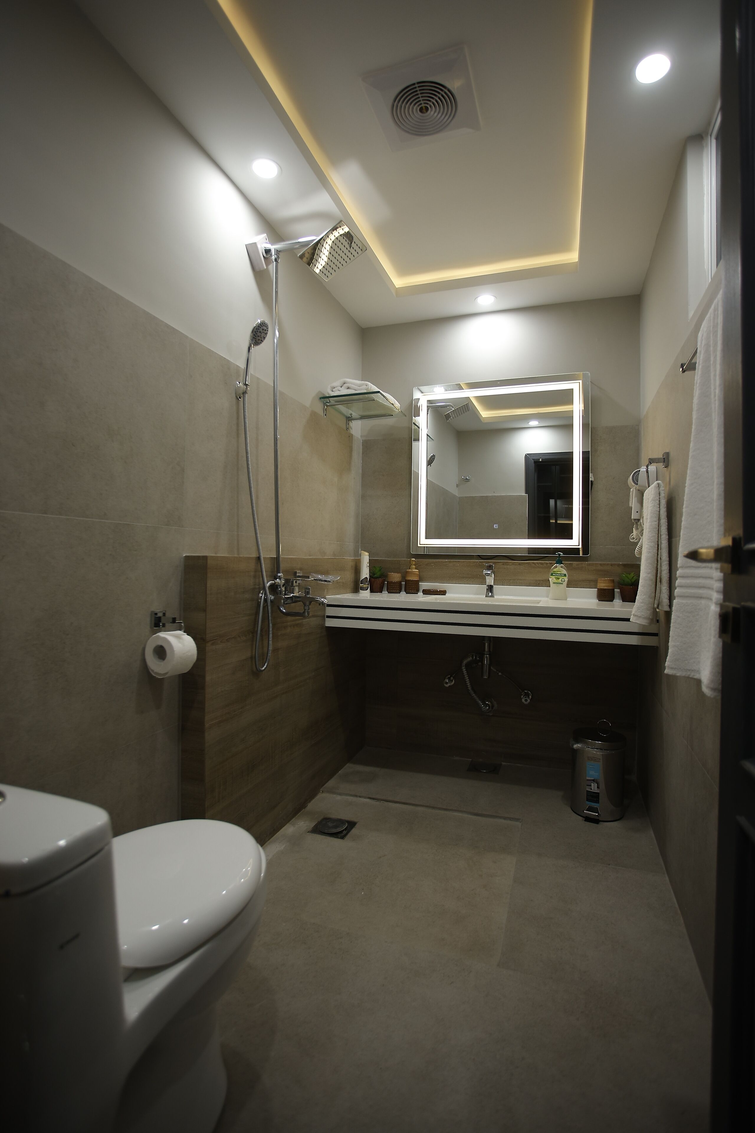 Egy modern fürőszoba, amelyben WC, mosdókagyló és zuhanyzó található.