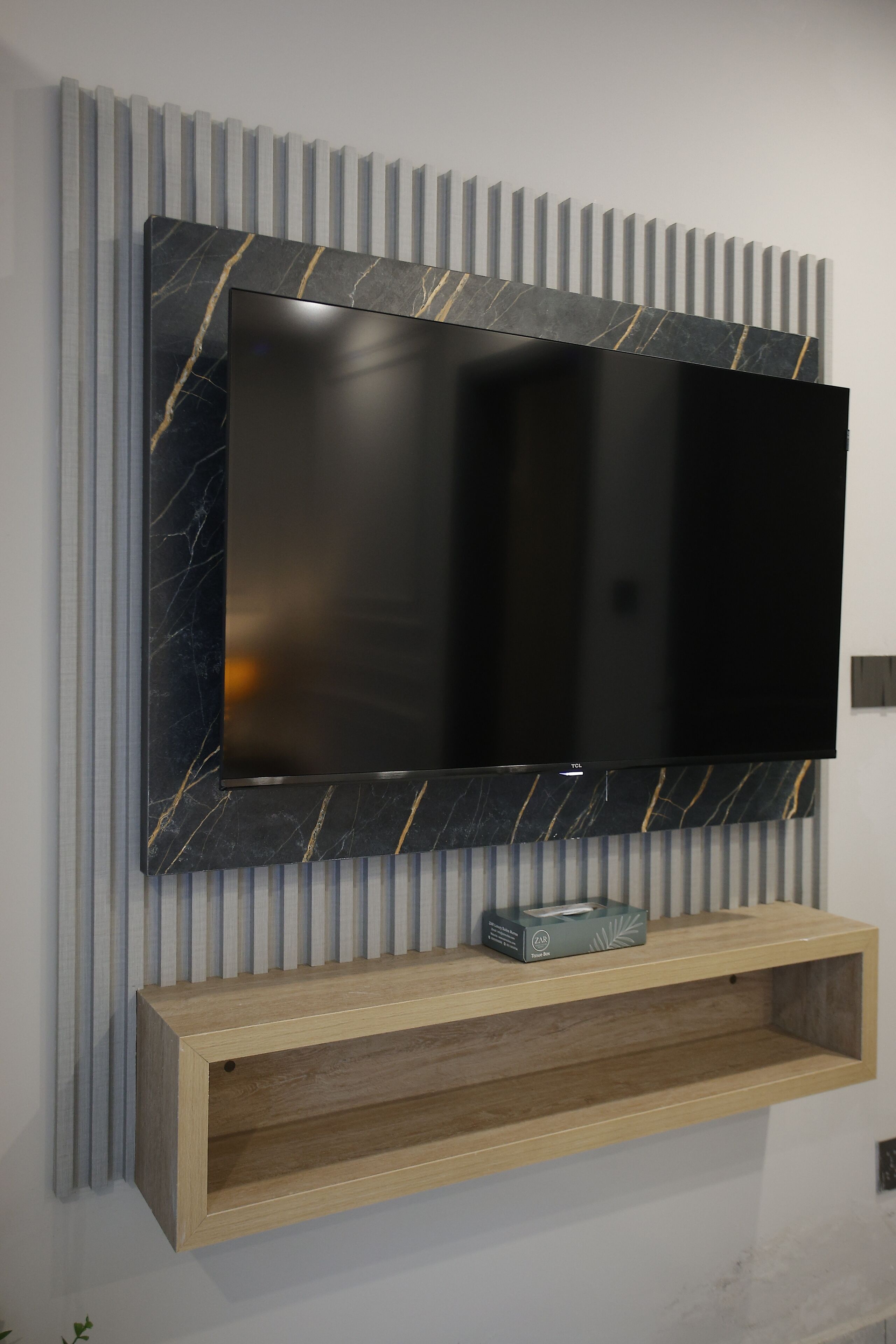 Un televisor de pantalla plana montado en una pared con diseño que imita el mármol.