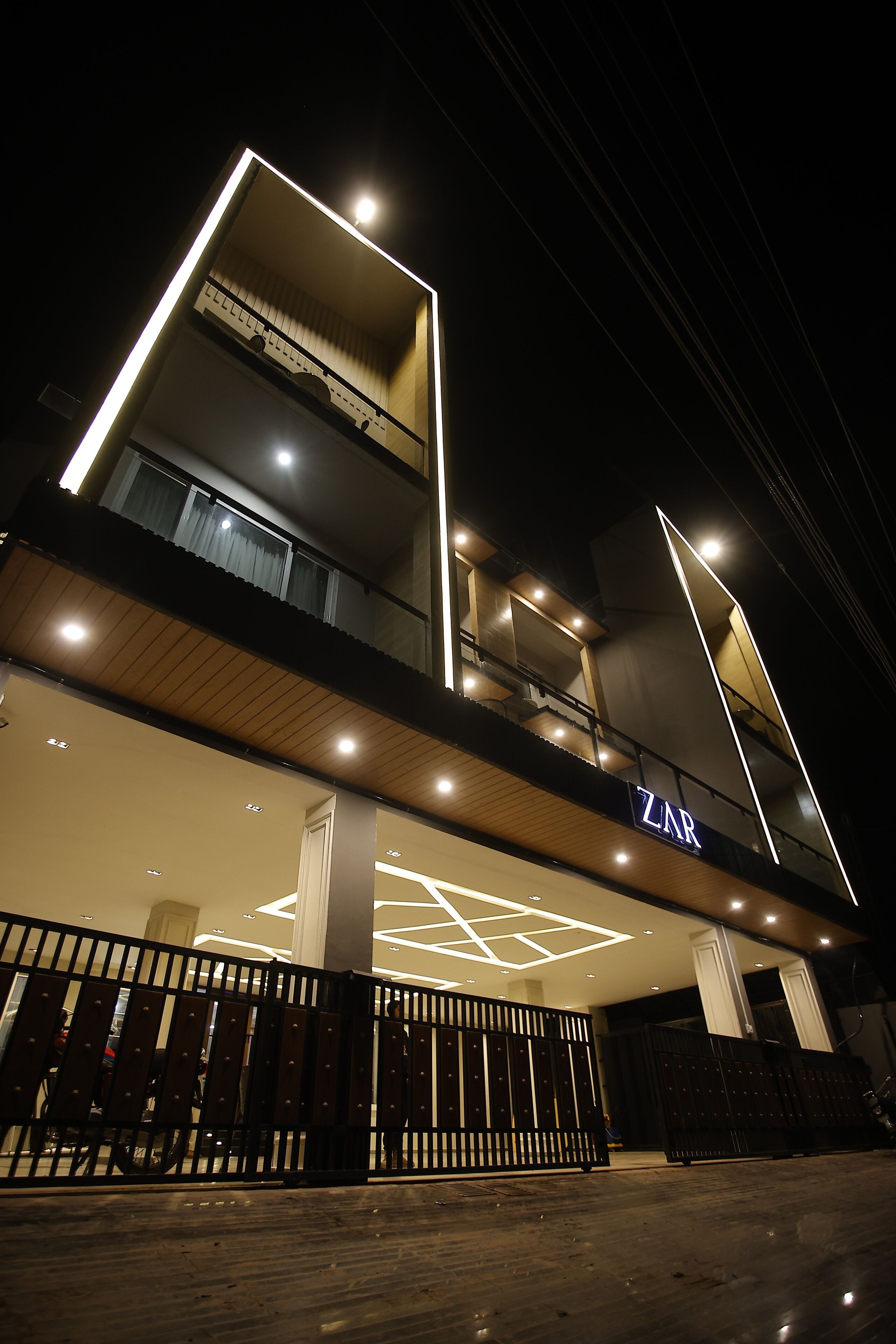 Un edificio moderno con un llamativo letrero 'ZAR', varios balcones y un diseño de luces geométricas en la fachada.