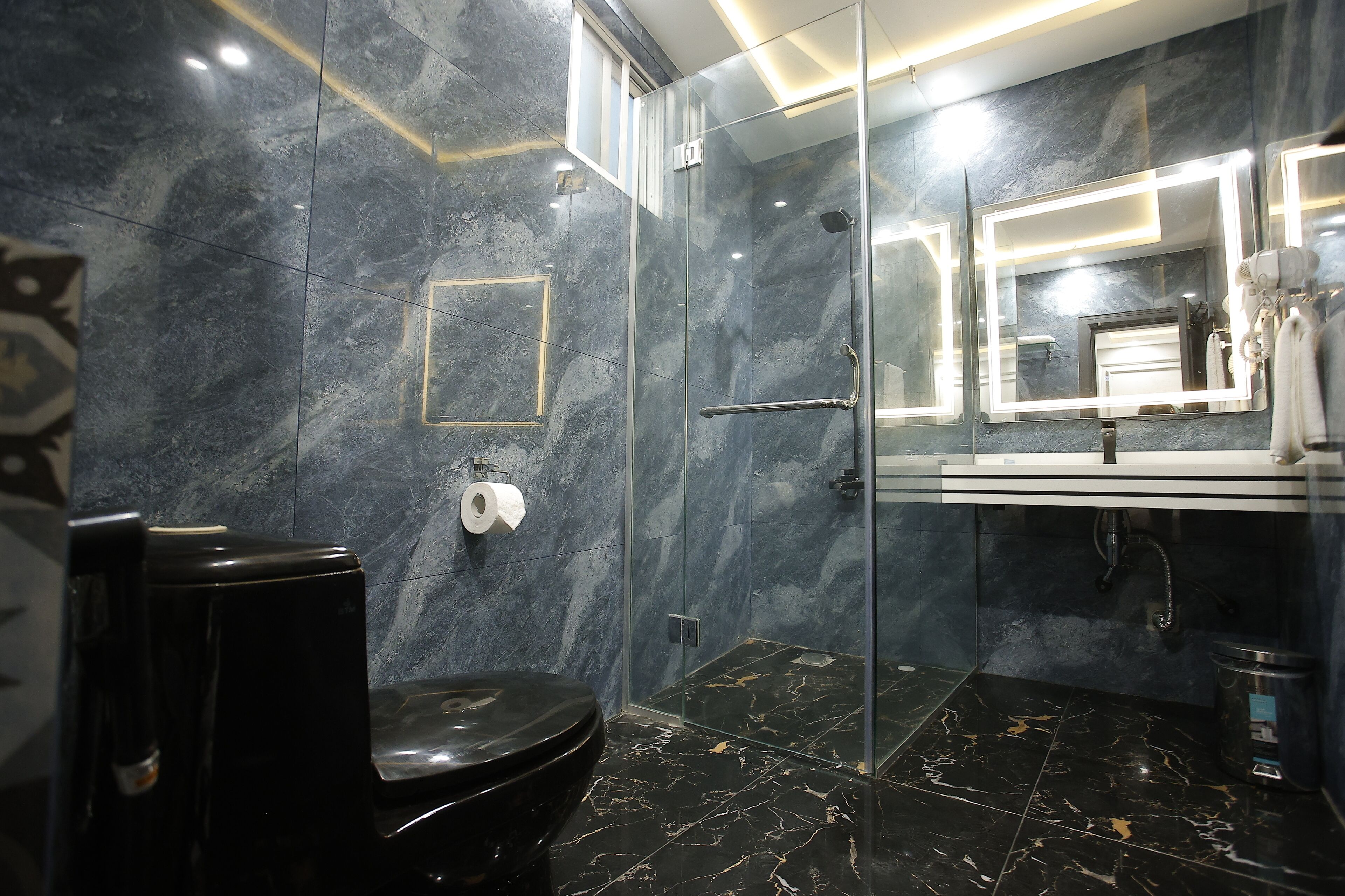 Un baño moderno con cabina de ducha de vidrio, inodoro, lavabo con espejo y perchero para toallas.