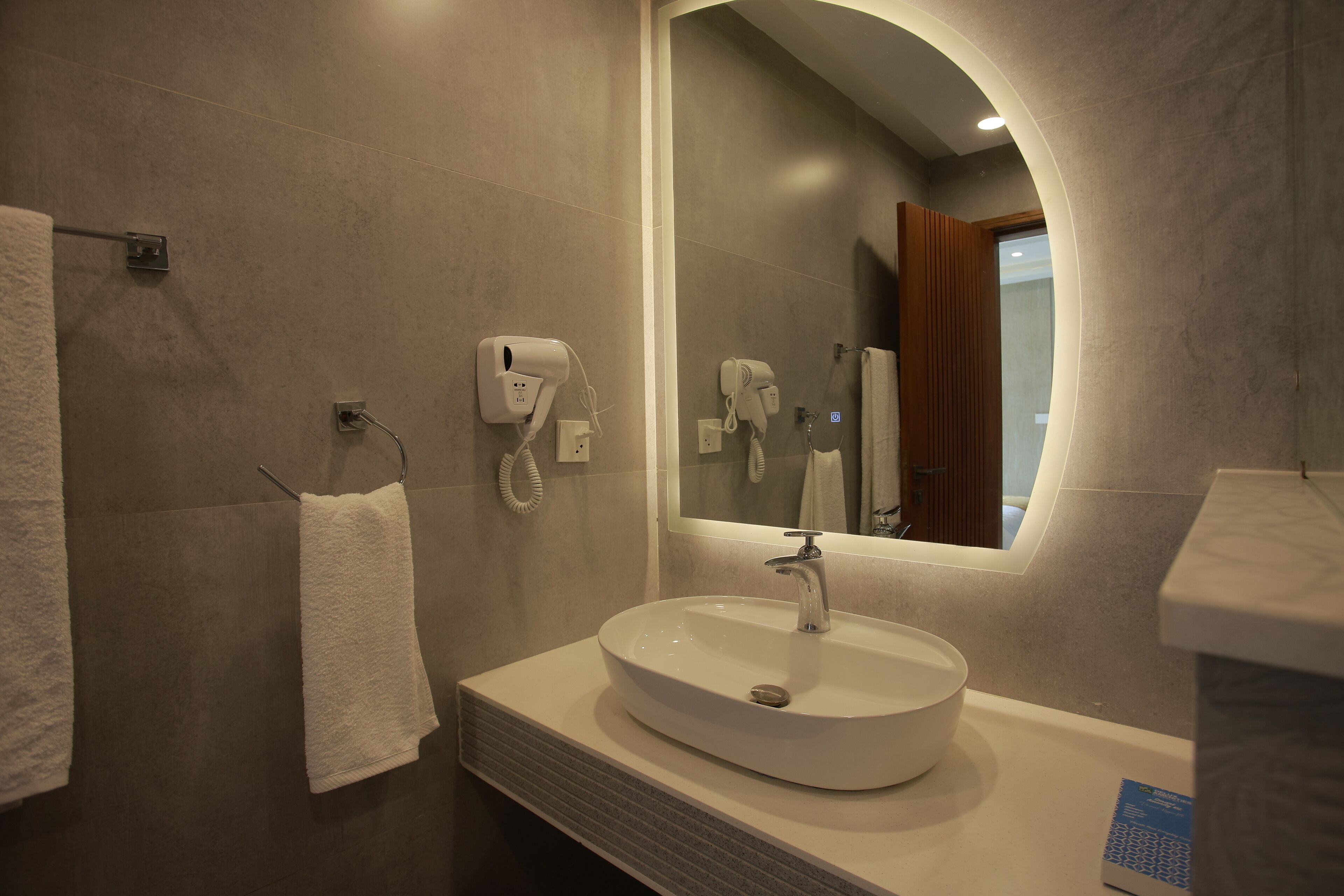 Un baño con lavamanos blanco, toallero y secador de pelo.