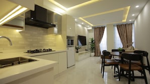 A modern kitchen with a built-in stove, a microwave, and a sink. There is a dining area with a table and chairs.