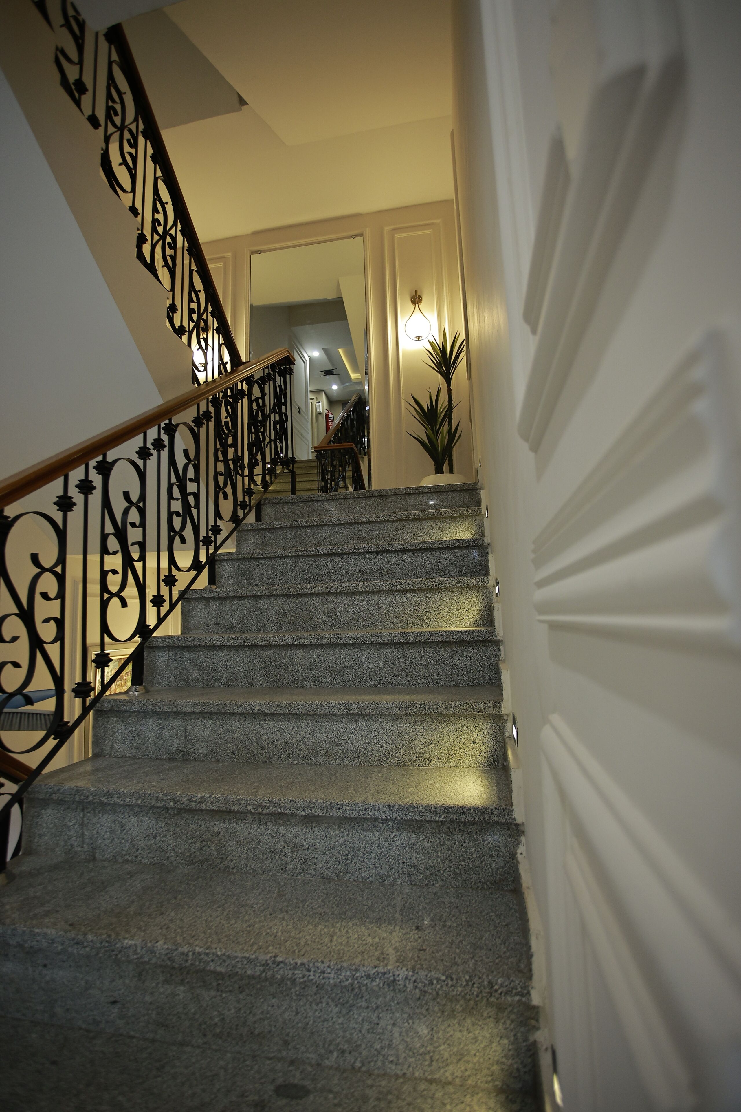 Una escalera con barandilla de hierro negro y una lámpara arriba.