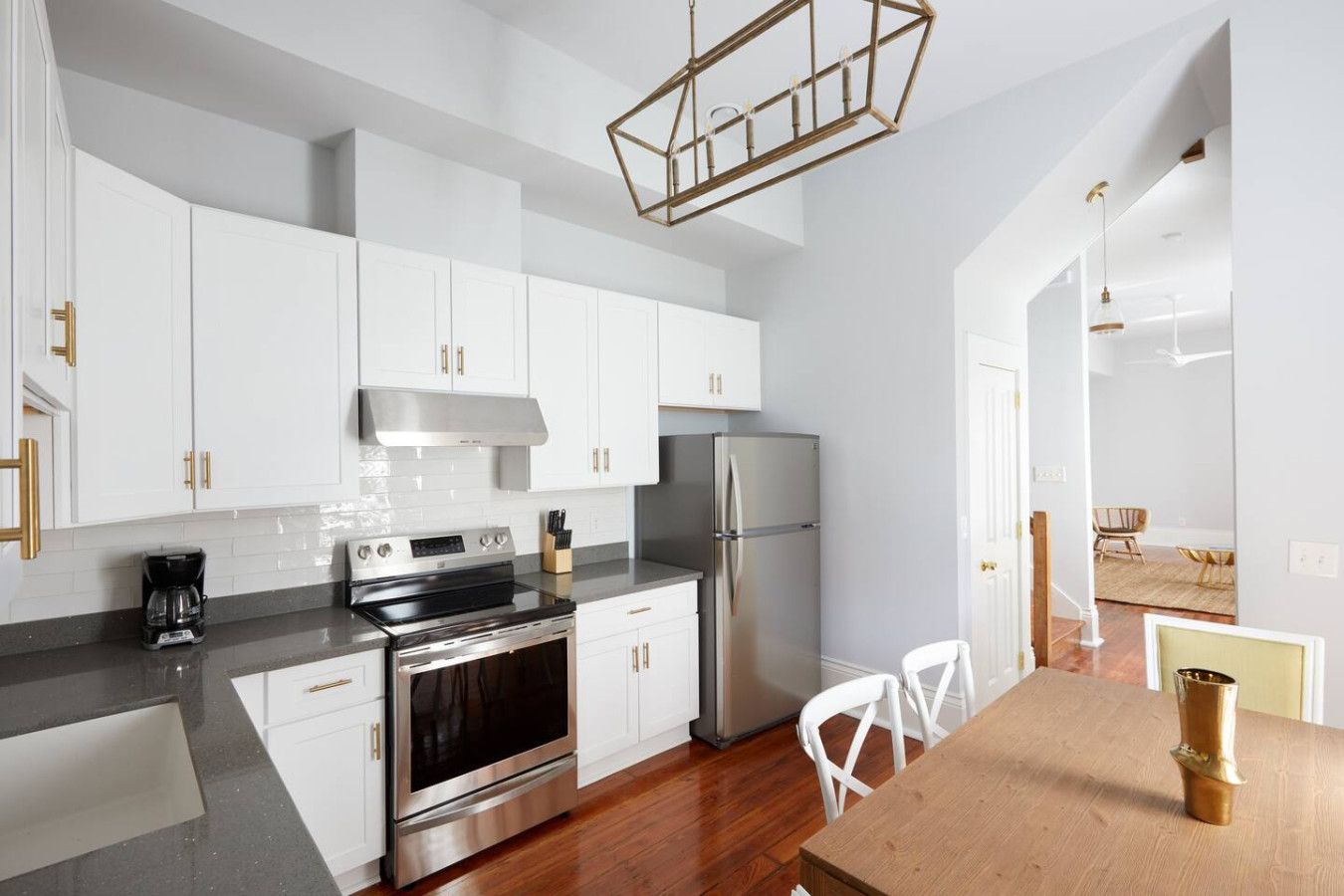 A modern kitchen with white cabinets, stainless steel appliances, and a wooden dining table.