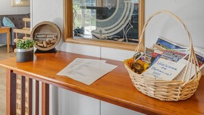 A wooden reception desk with a welcome sign, a basket of magazines, a small plant, and a 'Happy Hour' sign. - Nature-filled escape near Seneca Falls—sleep 8, explore wineries, and unwind in total comfort. (Seneca Falls)