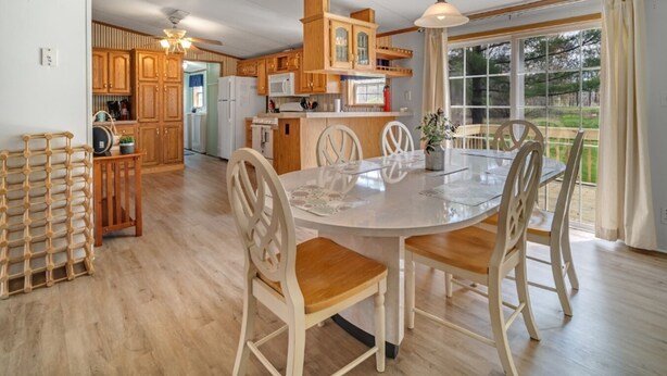 A spacious kitchen with wooden cabinets, a dining table with chairs, and a large window offering a view of the outdoors. - Nature-filled escape near Seneca Falls—sleep 8, explore wineries, and unwind in total comfort. (Seneca Falls)