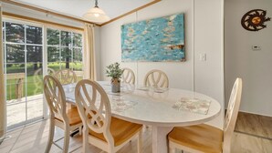 A dining area with a round table, four chairs, a vase with flowers, and a painting on the wall. - Nature-filled escape near Seneca Falls—sleep 8, explore wineries, and unwind in total comfort. (Seneca Falls)